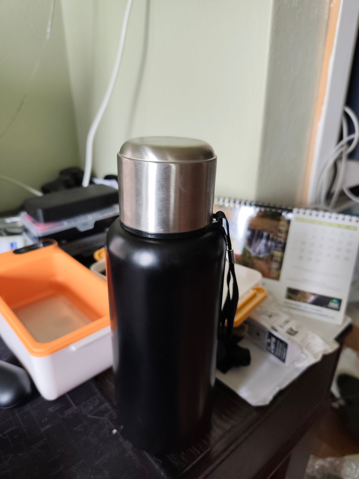 Real-life photo of the black 1200ml 316 stainless steel thermos sample assembled with stainless-steel cup lid and carrying strap