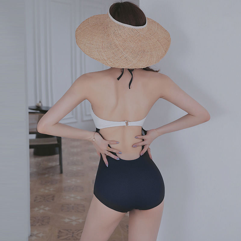 Rear view of blue and white halter one-piece swimsuit showing neck ties, white back band and large open-back cut-out