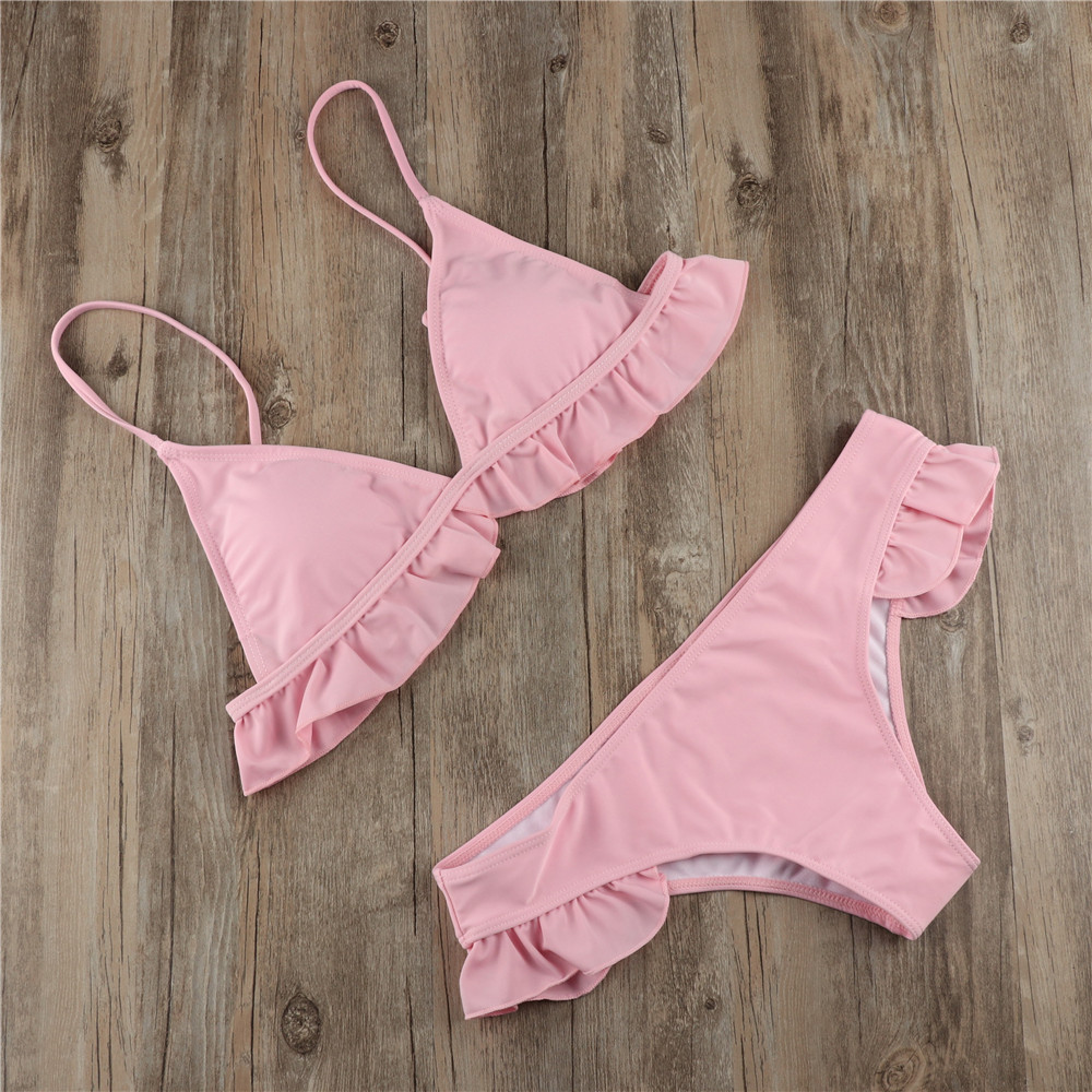 Pink two-piece bikini arranged diagonally on wood with ruffled top and matching frilled bottoms