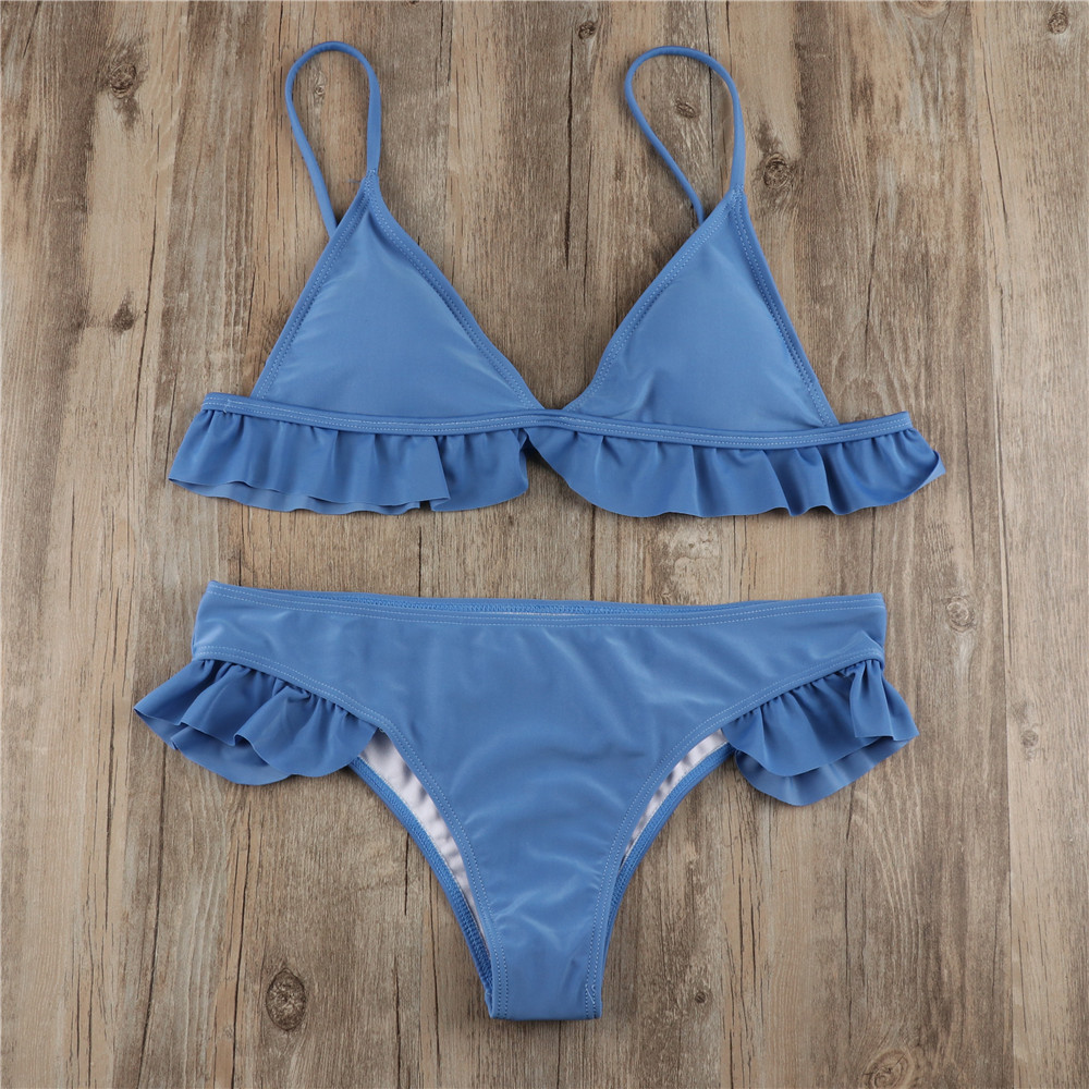 Front flat-lay of blue ruffle-trim bikini top and matching bottoms on wood