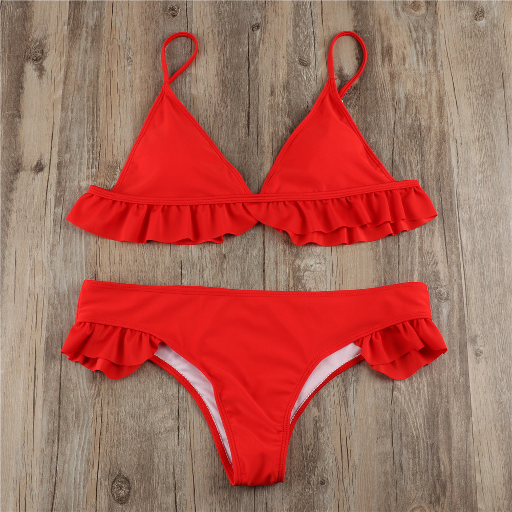 Red ruffle-trim bikini top and matching bottoms laid flat on wood